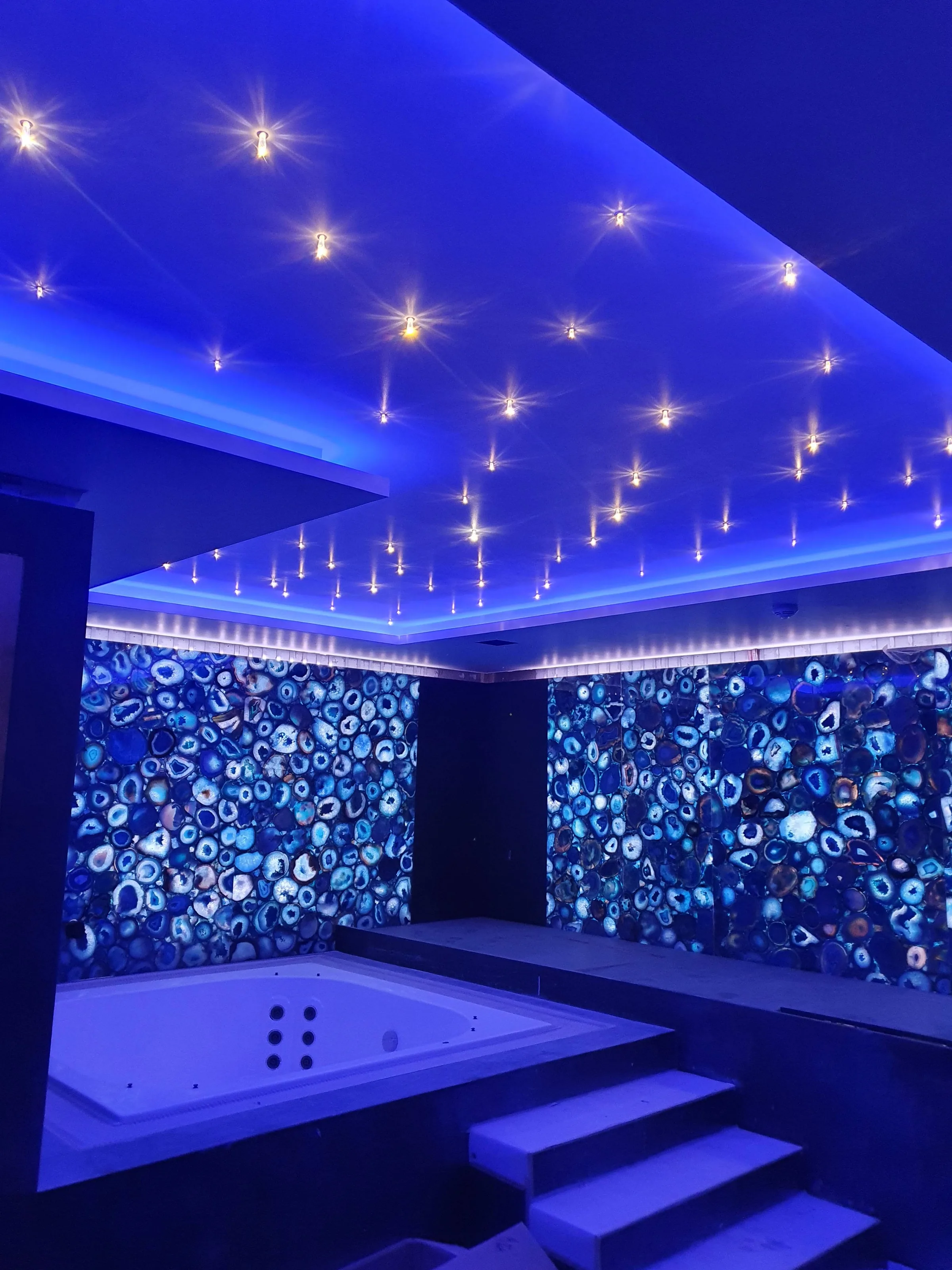 Espace spa avec jacuzzi, panneaux d'agate bleue et plafond etoile LED